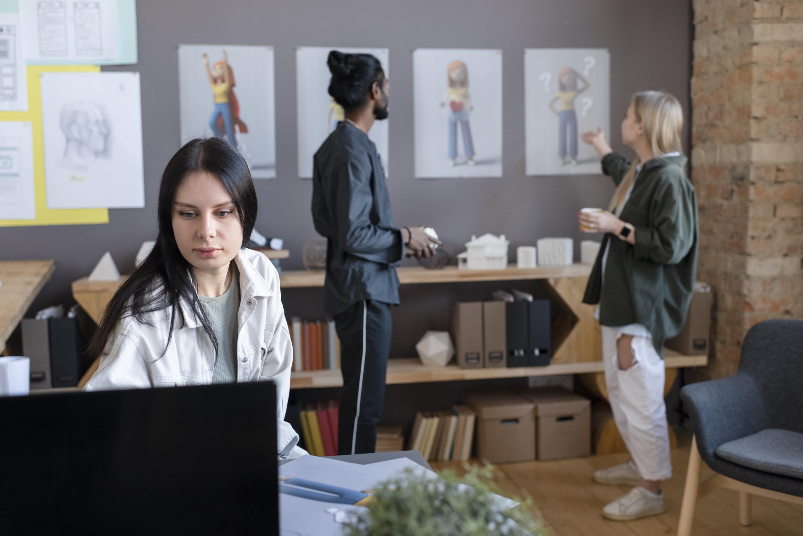 Team reviewing character designs while a colleague works on a computer