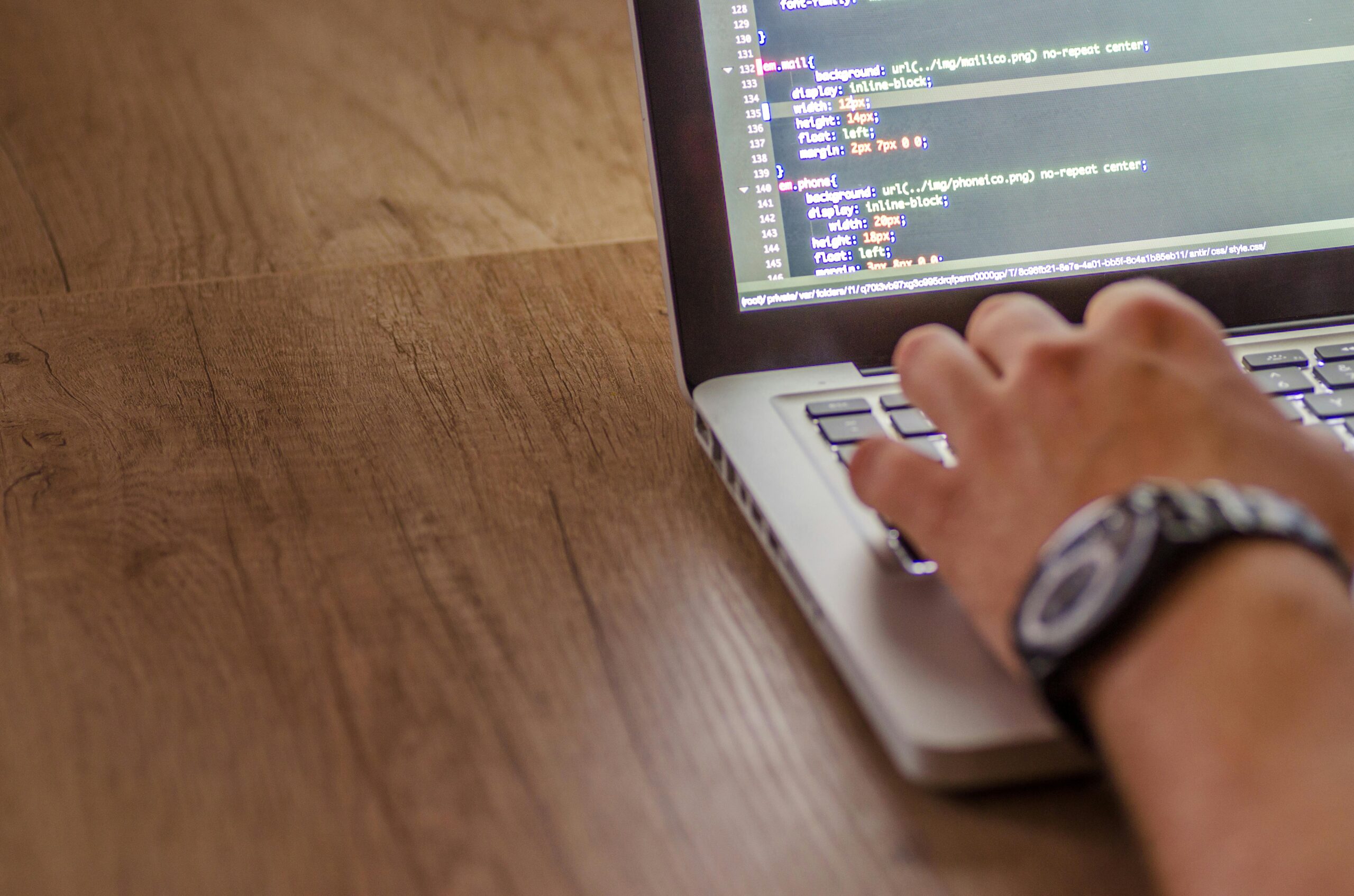 A person coding on a laptop with CSS code visible on the screen